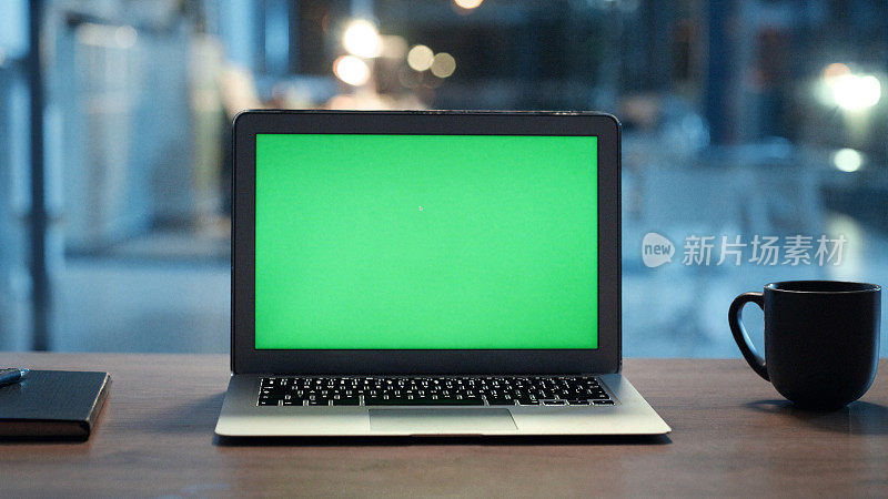 色度键绿色屏幕上的笔记本电脑或空CGI, copyspace桌面电脑显示模板的特写。晚上在办公桌上模拟电脑显示器，旁边是笔记本，钢笔和杯子或马克杯。